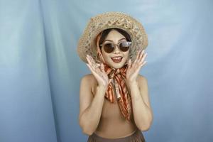 Traveling concept of a young Asian happy woman isolated by a blue background. photo