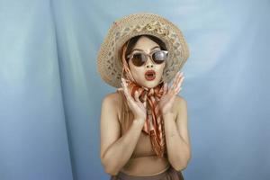 The traveling concept of a young Asian woman shocked and isolated by a blue background. photo