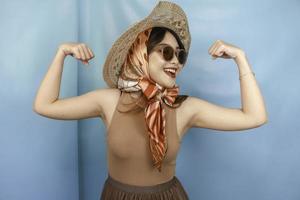 Young Asian strong woman showing her biceps isolated by a blue background photo