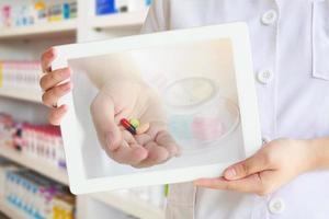 pharmacist showing tablet computer over pharmacy background photo