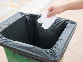 hand putting paper into trash bin photo