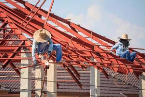 welder workers installing steel frame structure of the house roof at building construction site