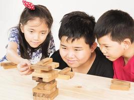 Children is playing a wood blocks tower game for practicing their physical and mental skill photo