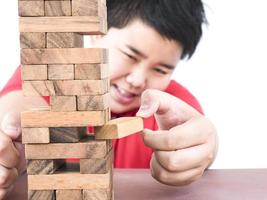 un niño asiático está jugando un juego de torre de bloques de madera para practicar habilidades físicas y mentales foto