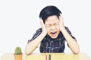 chico enojado está gritando mientras hace su tarea foto
