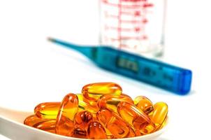 Fish oil with thermometer and glass on white background photo