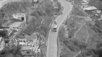 Aerial top view of traffic vehicles driving at mountains roads at Nainital, Uttarakhand, India, View from the top side of mountain for movement of traffic vehicles Black and White video