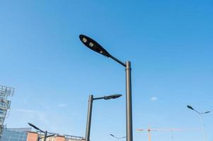 Abstract image of a modern street lamp on a lamppost against a blue sky. Lighting equipment for the city, parking photo