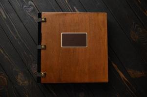 un viejo álbum de fotos con tapa de madera y un escudo sobre una mesa rústica. logotipo gratis