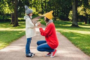 People, relationship, parenthood and childhood concept. Beautiful mother plays with her little daughter in park, gives yellow leaf, have sincere emotions and feeling or love to her lovely daughter photo