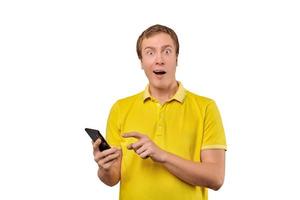 Surprised young man with smartphone, funny guy holding phone isolated on white background photo