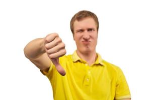 Unhappy annoyed man in yellow T-shirt showing thumbs down gesture isolated on white background photo