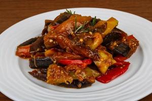 Roasted vegetables on the plate and wooden background photo