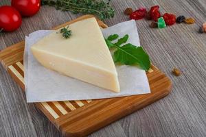 queso parmesano en plato de madera y fondo de madera foto