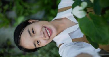 retrato de uma jovem jardineira asiática feliz vendendo on-line nas mídias sociais e olhando para a câmera no jardim. selfie de mulher com telefone celular. verdura em casa, venda online e hobby. video