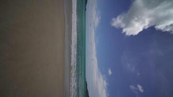 vídeo vertical pov oceano areia praia e textura da superfície da água. ondas espumosas com céu e nuvens. bela praia tropical e palmeiras. incrível litoral arenoso com ondas do mar branco. conceito de natureza. video