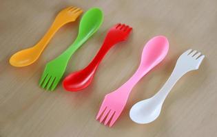 Colorful plastic cutlery on table background photo