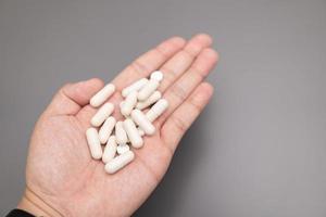 mano de un hombre con pastillas blancas en la palma. concepto médico de tratar enfermedades con medicamentos. foto