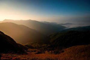 beautiful blue sky and mountains in the mornings of summer. And there is a sea of mist inserted between the valleys With dry meadows foreground photo