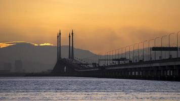 el sol naranja de lapso de tiempo se levanta sobre el puente de penang