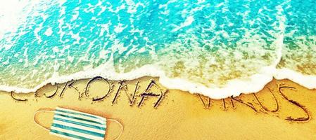 corona virus escrito en la arena de vacaciones foto