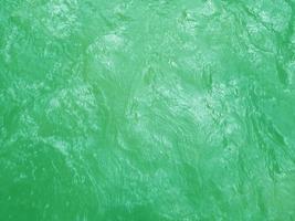 Defocus blurred transparent green colored clear calm water surface texture with splashes and bubbles. Trendy abstract nature background. Water waves in sunlight. Green water background. photo