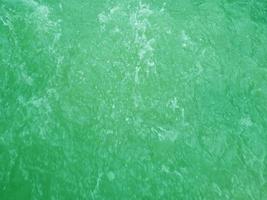 Defocus blurred transparent green colored clear calm water surface texture with splashes and bubbles. Trendy abstract nature background. Water waves in sunlight. Green water background. photo