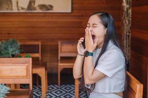 mujer asiática tomando café en la cafetería y usando el teléfono para trabajar en marketing comercial en línea foto