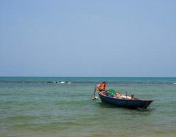 paisaje mirada vista pequeño barco de pesca de madera antiguo estacionado costa el mar. después de la pesca de los pescadores en el pequeño pueblo es pequeña pesca local. cielo azul, nubes blancas, clima despejado, playa phala, rayong foto