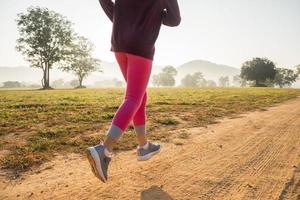 niña feliz corriendo en la pradera en verano en la naturaleza. llamarada cálida de la luz del sol. el pequeño asiático corre en un parque. deportes al aire libre y fitness, ejercicio y aprendizaje de competencias para el desarrollo de los niños. foto