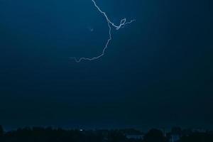 Lightning in sky over city. Bright flashes on dark night. Thunderclouds and electricity discharges in atmosphere. photo