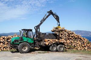 Forest log truck tree harvester unloading tree logs. Forest industry photo