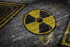 Ilustración 3d que representa una pared de ladrillos con una señal de peligro radiactivo y líneas amarillas y negras foto