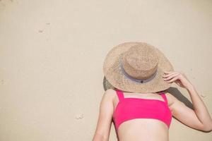 mujer turista en traje de baño rosa y sombrero, viajera feliz tomando el sol en la playa paraíso en las islas. destino, pasión por los viajes, viaje por asia, verano tropical, vacaciones y concepto de vacaciones foto