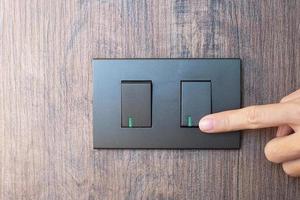 el dedo masculino de primer plano se enciende o apaga en el interruptor de luz en la pared en casa. conceptos de ahorro de energía, energía, electricidad y estilo de vida foto