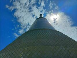 Pagoda view from below was shadowed. Blue sky with white blur clouds. The sun shines on the right. photo