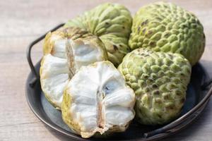 Custard apple and halved fruit on wooden background photo