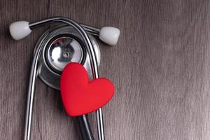Stethoscope with red heart on gray background. Heart health care concept. photo