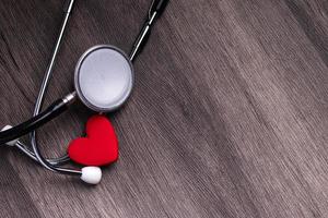 estetoscopio con corazón rojo sobre fondo gris. concepto de atención de la salud del corazón. foto