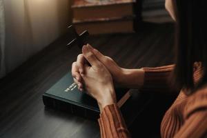 mujer sentada y estudiando las escrituras. la cruz de madera en las manos. conceptos de educación cristiana las sagradas escrituras se abren y oran a dios. foto