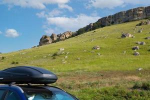 car for travel with a roof rack on a mountain road, against the backdrop of the White Rock. photo