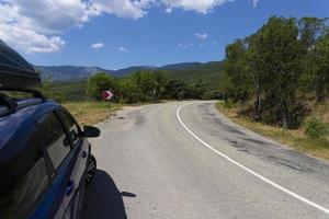 coche de viaje familiar con portaequipajes en una carretera de montaña. foto