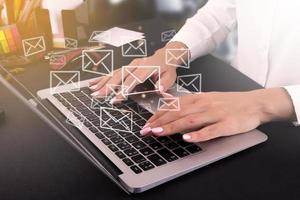 Business woman working in the office using a laptop with email icons on a virtual screen, sending email, direct marketing, online message, email concept. photo