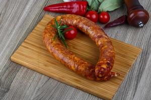 Sausage ring on wooden plate and wooden background photo