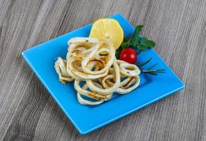 Squid rings on the plate and wooden background photo