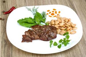 Roasted beef on the plate and wooden background photo