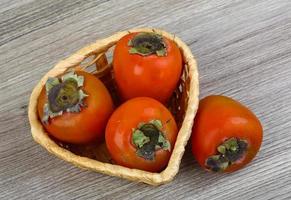 Persimmon in a basket on wooden background photo