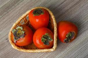 Persimmon in a basket on wooden background photo