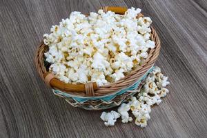 palomitas de maíz en un recipiente sobre fondo de madera foto