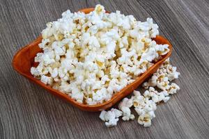 Popcorn in a bowl on wooden background photo